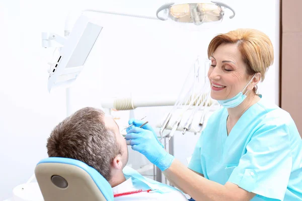 Dentist examining patient's teeth in clinic — Stock Photo, Image