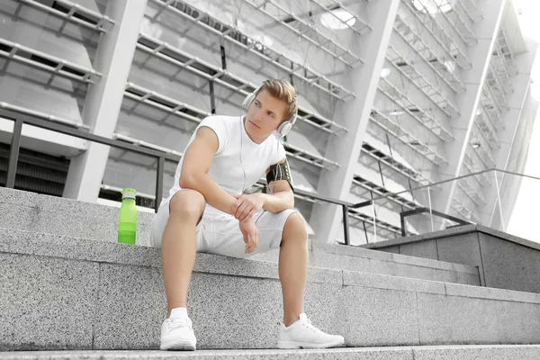 Young man with headphones sitting on  stairs — Stock Photo, Image