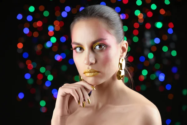 Smuk kvinde med ferie makeup mod defokuserede lys - Stock-foto