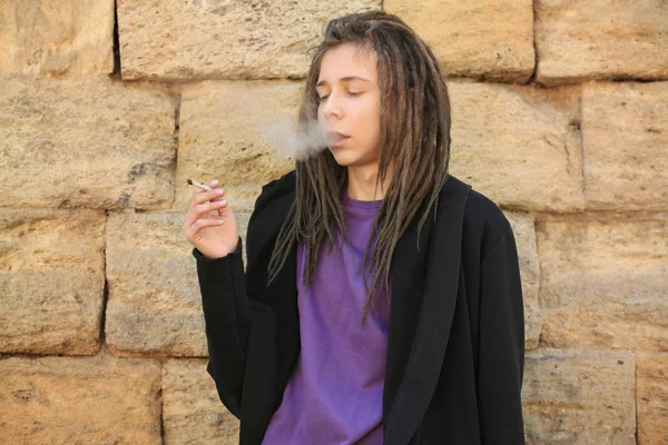 Menino fumando erva no fundo da parede de pedra — Fotografia de Stock
