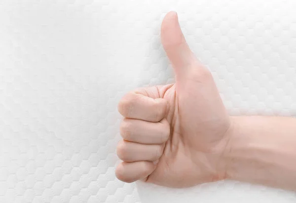 Male hand showing thumb up sign and orthopedic pillow on background. Healthy posture concept — Stock Photo, Image