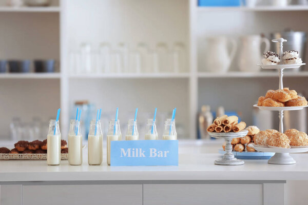 Bottles, desserts and card with text MILK BAR 