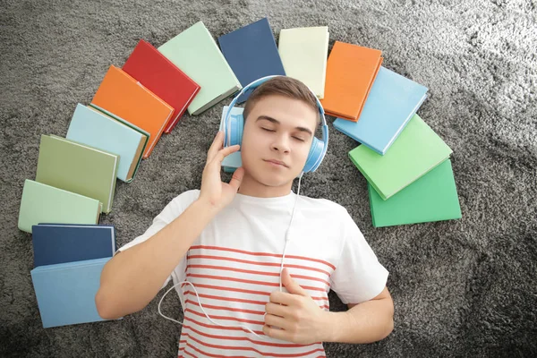 Молодой человек лежит на полу и слушает аудиокнигу — стоковое фото