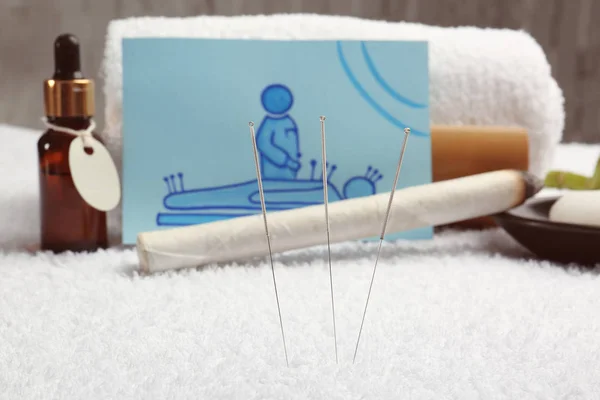 Acupuncture needles and blurred supplies on background