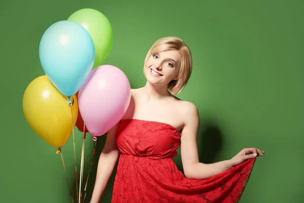 Gyönyörű nő gazdaság tarka hőlégballonok zöld háttér — Stock Fotó