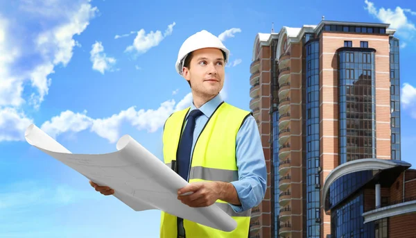 Ingenieur mit Projektzeichnung und modernem Gebäude im Hintergrund — Stockfoto