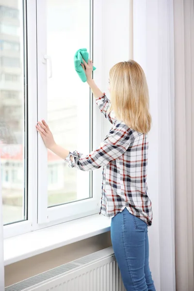 Jonge vrouw schoonmaak venster — Stockfoto