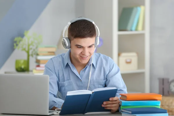 Fiatal ember ül az asztalnál, és hallgatta audio könyv — Stock Fotó