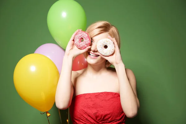 Красива жінка тримає пончики на зеленому тлі — стокове фото