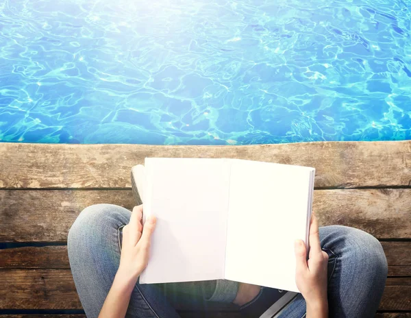 Жінка читає книгу біля води — стокове фото