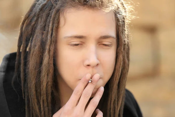 Young boy smoking weed on blurred background — Stock Photo, Image