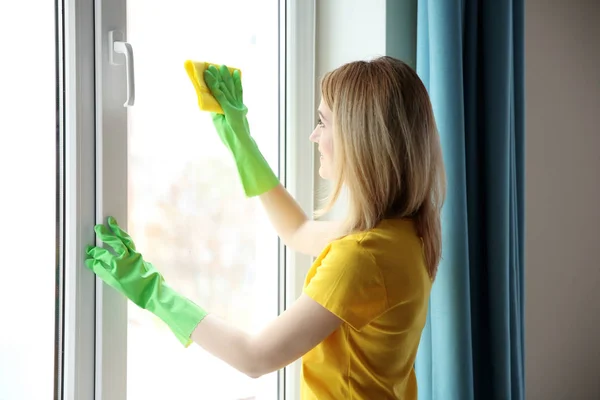 Mujer joven ventana de limpieza — Foto de Stock