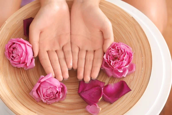 Mãos femininas em tigela de madeira spa — Fotografia de Stock