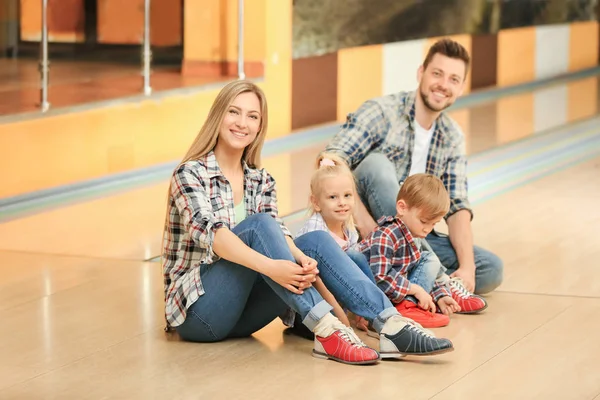 Family sitting on floor in bowling club — Stock Photo, Image