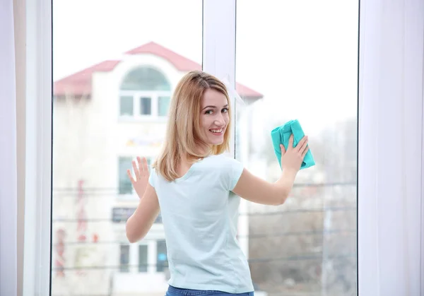 Jonge vrouw schoonmaak venster — Stockfoto