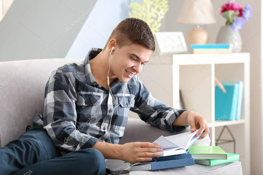 Young man listening to audio book at home