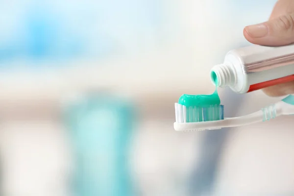 Cepillo de dientes y pasta de dientes sobre fondo borroso — Foto de Stock