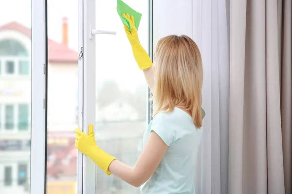 Mujer joven ventana de limpieza — Foto de Stock