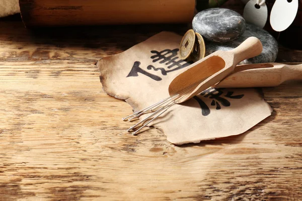 Aiguilles d'acupuncture, cuillères, pièces et papier sur fond en bois — Photo