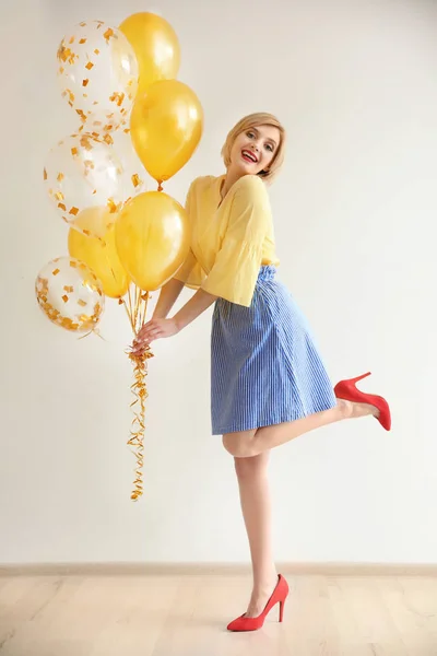 Hermosa mujer sosteniendo globos de aire contra la pared blanca — Foto de Stock