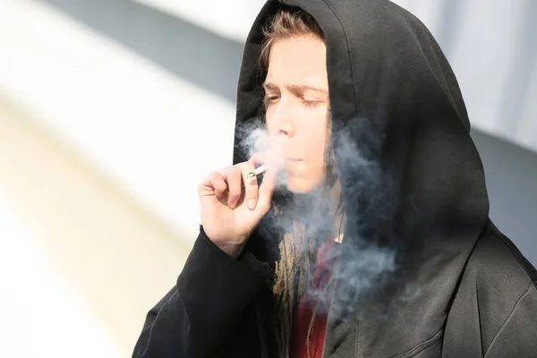 Kleiner Junge raucht Unkraut auf hellem Hintergrund — Stockfoto