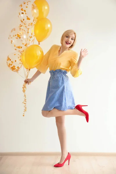 Mooie vrouw met lucht ballonnen tegen de witte muur — Stockfoto