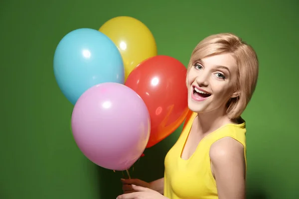 Beautiful woman holding multicolored air balloons on green background — Stock Photo, Image