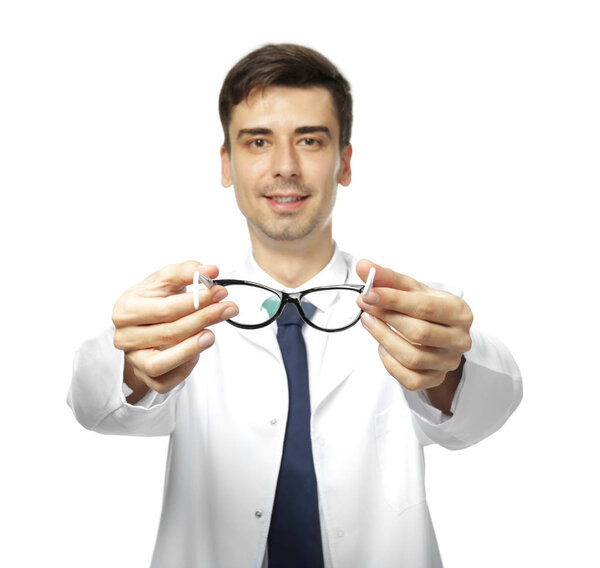 Handsome young ophthalmologist holding glasses on white background