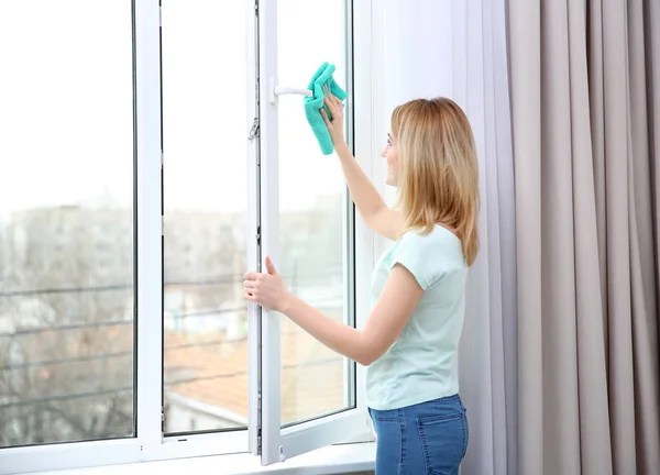 Mujer joven ventana de limpieza — Foto de Stock