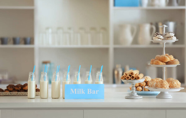 Bottles, desserts and card with text MILK BAR 