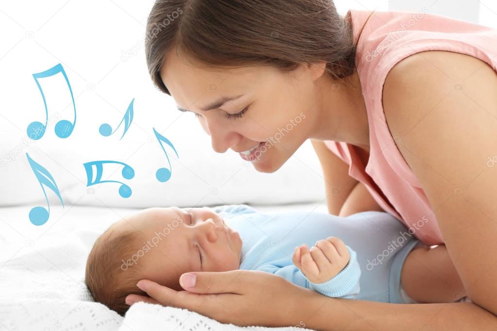 Mother with sleeping baby on bed. Lullaby songs and music concept