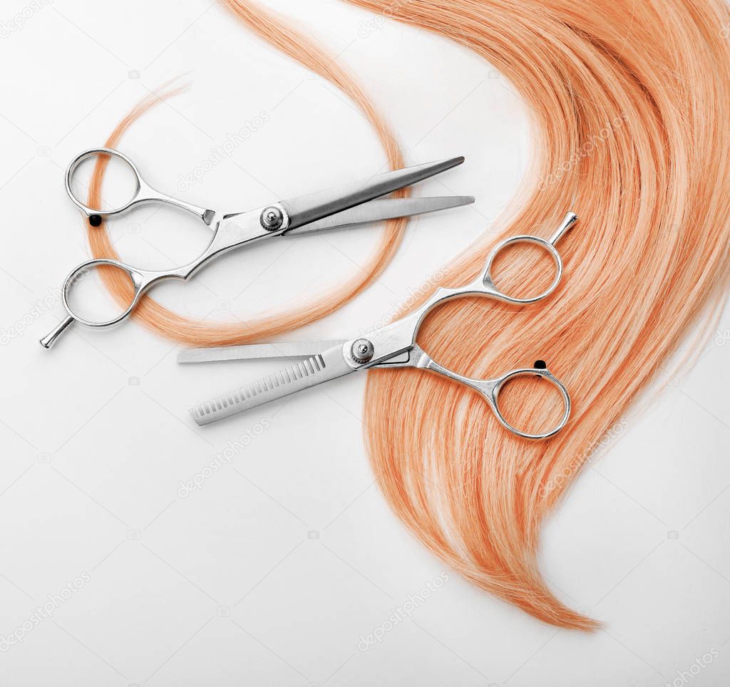 Strawberry blonde hair and scissors on white background