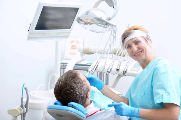 Dentista examinando los dientes del paciente en la clínica —  Fotos de Stock