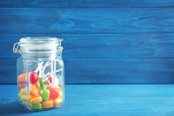 Different candies in glass jar on wooden background — Stock Photo, Image