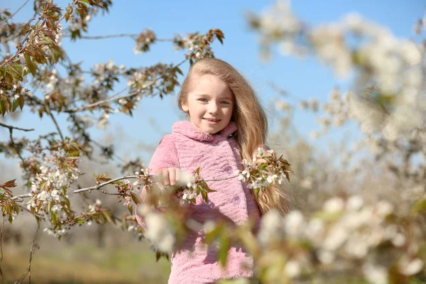 Mała dziewczynka w pobliżu kwitnące drzewo — Zdjęcie stockowe
