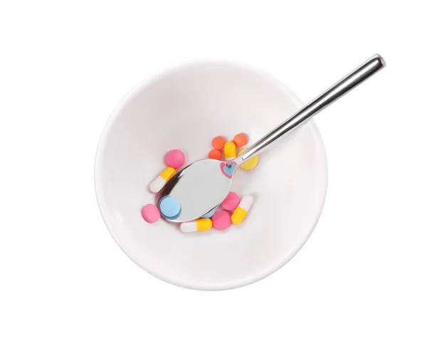 Ложка в миске с различными таблетками — стоковое фото