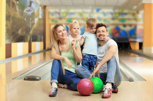 Familia feliz sentado en el suelo en el club de bolos — Foto de Stock