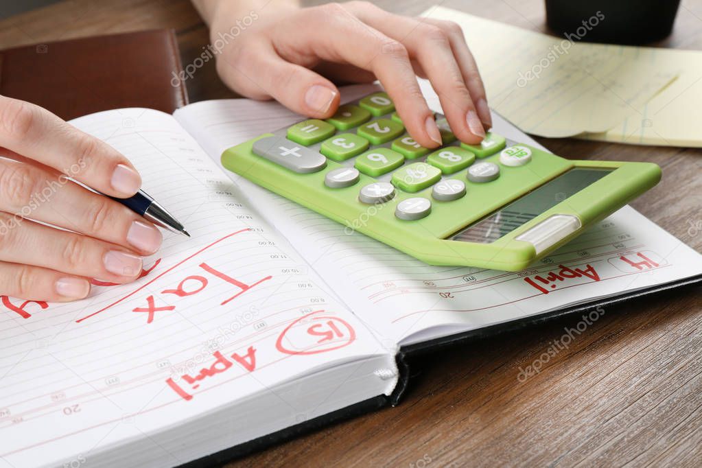 Woman sitting at table with calculator and notebook