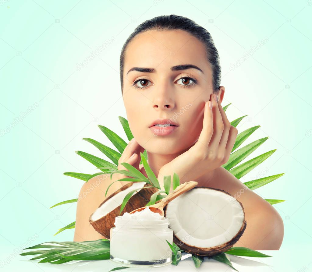 Coconut oil for skin. Young woman and cosmetic on color background