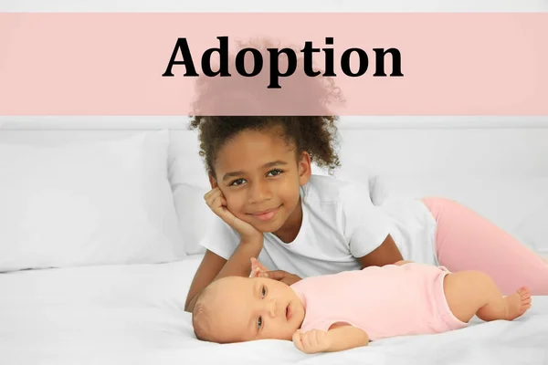 Concepto de adopción. Lindo bebé y hermana mayor acostada en la cama —  Fotos de Stock