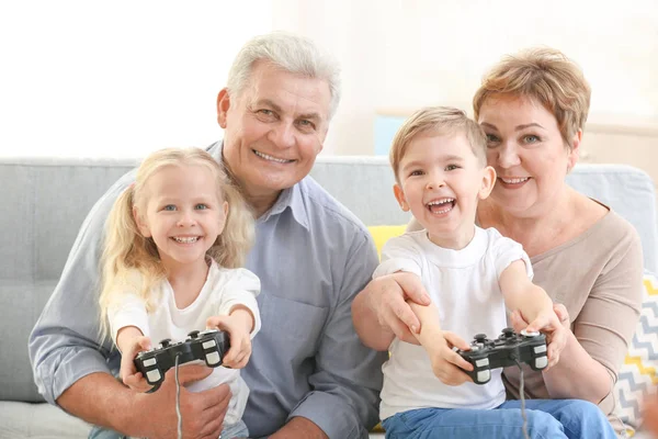祖父母和孙辈一起在家里玩电子游戏 — 图库照片