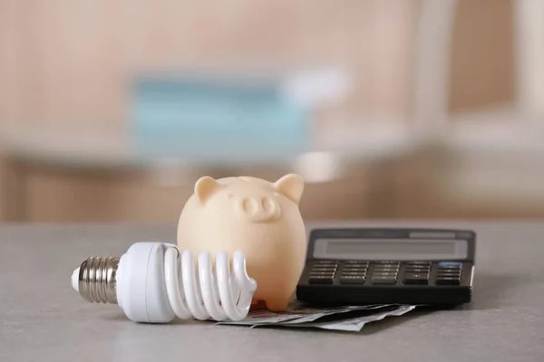 Het opslaan van elektrische energie concept. Keramische piggy bank met Rekenmachine en geld op tafel — Stockfoto