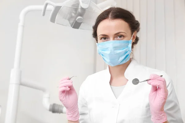 Dentist with mirror and periodontal explorer in clinic — Stock Photo, Image