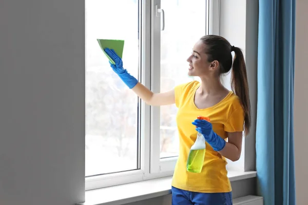 Молодая женщина моет окно — стоковое фото