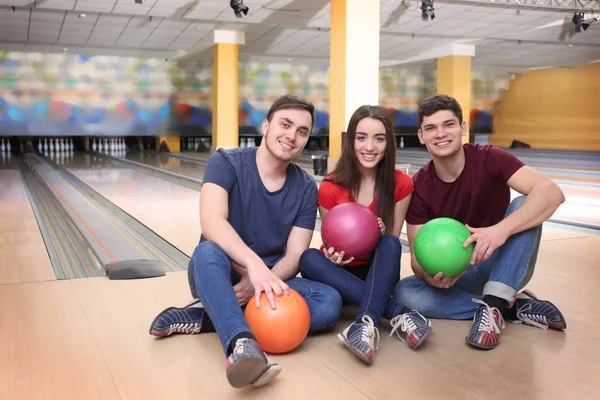 Amis assis sur le sol dans le club de bowling — Photo