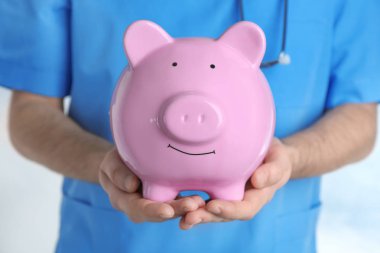 Erkek doktor Piggy banka, holding kapatın. Sağlık sigortası kavramı