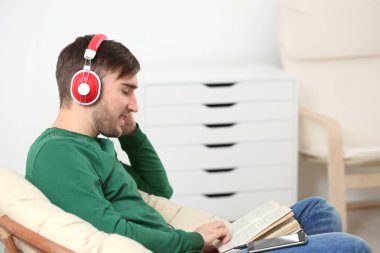 Audiobook kavramı. Kitap ve kulaklık ile yakışıklı genç