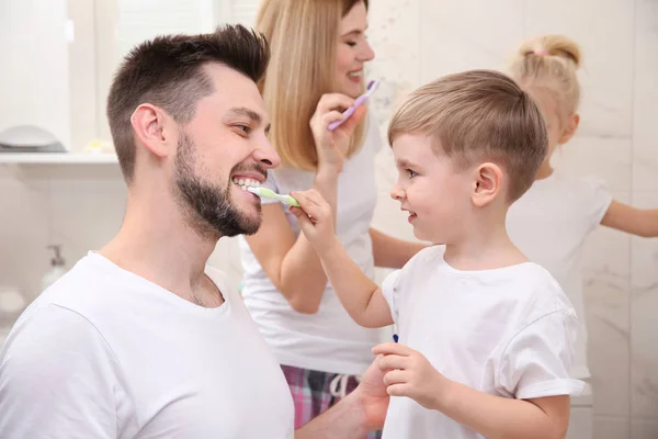 Мальчик помогает отцу чистить зубы — стоковое фото
