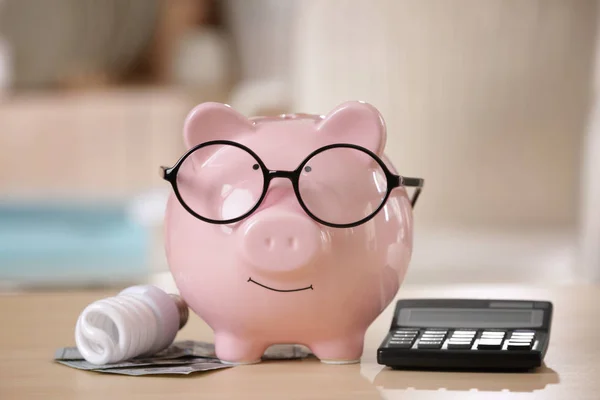 Saving electric power concept. Ceramic piggy bank with calculator and money on table