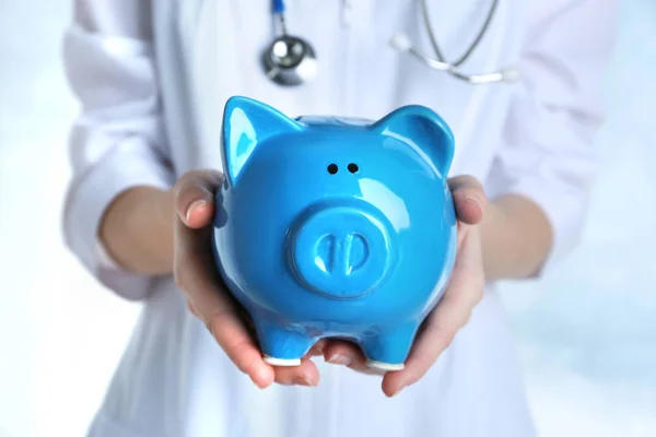 Kvinnliga läkare håller piggy bank, närbild. Begreppet medicinsk försäkring — Stockfoto